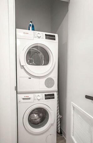 Eine übereinander gestellte Waschmaschine und ein Trockner in einem Flur.