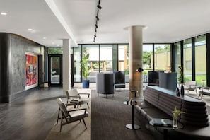 Un hall dâentrĂ©e moderne avec un comptoir dâaccueil, un espace salon et de grandes fenĂȘtres.