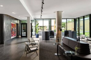 En moderne lobby med et stort siddeområde, en receptionsdisk og store vinduer med udsigt til det fri.