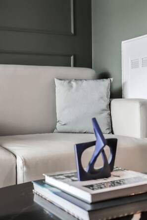 En moderne stue med sofa, sofabord med bøger og en dekorativ genstand, samt en væg med paneler.