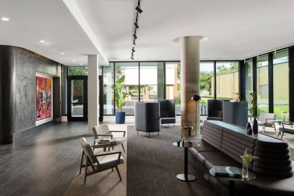 A modern lobby with a large seating area, a reception desk, and large windows offering a view of the outdoors.