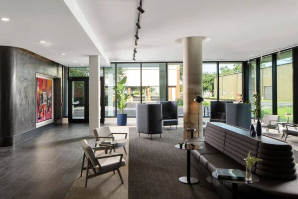 En moderne lobby med et stort siddeområde, en receptionsdisk og store vinduer med udsigt til det fri.