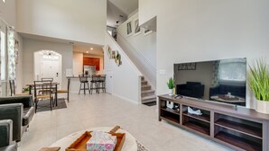 Amplia sala de estar con una escalera moderna, comedor y un televisor de pantalla plana grande.
