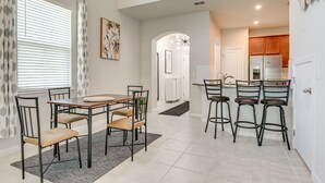 Una cocina moderna con una isla central, taburetes de bar y una zona de comedor con mesa y sillas.