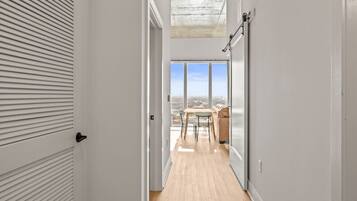 A narrow hallway with a wooden floor leading to a balcony with a table and chairs.