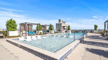 A rooftop pool with lounge chairs, a water slide, and a covered seating area.