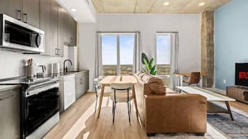 A modern kitchen with a dining area, a sofa, and a TV.
