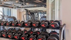 A gym with weight racks filled with dumbbells and a bench.