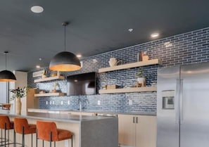 Una cocina moderna con protector contra salpicaduras de ladrillo, electrodomésticos de acero inoxidable y taburetes de bar.