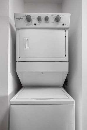 Una lavadora y secadora Whirlpool apiladas en un pequeño cuarto de lavado cerrado, con una sola puerta.