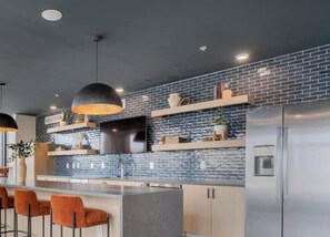 A modern kitchen with a brick backsplash, stainless steel appliances, and bar stools.