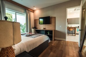 Een moderne hotelkamer met een groot bed, een bureau, een televisie en uitzicht op de omgeving.