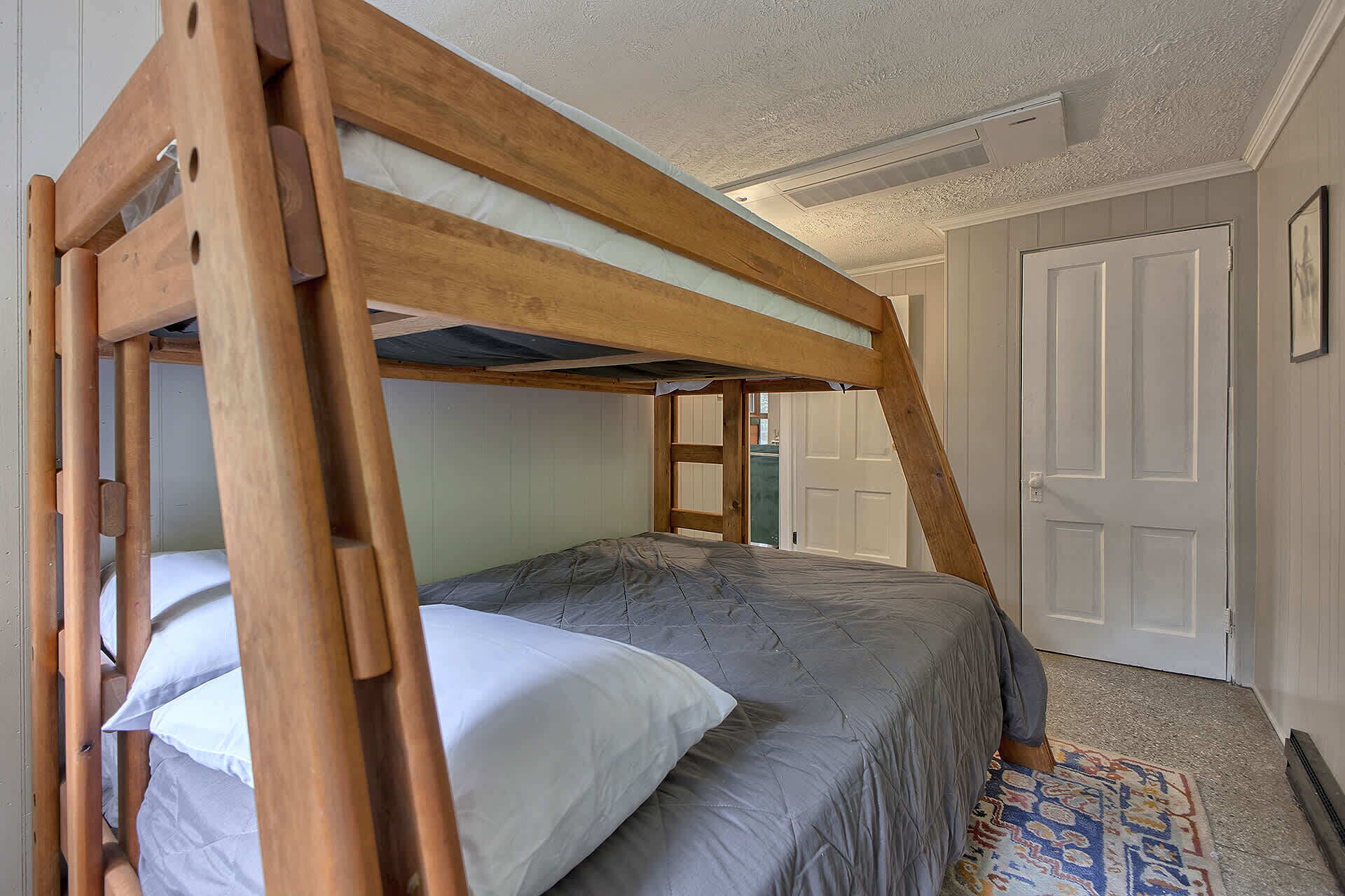 A bunk bed with a wooden frame and a gray mattress.