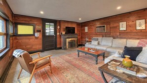 Una sala de estar acogedora con chimenea, paredes de madera, un sofá y un sillón.
