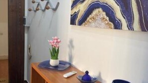 A wooden bench with a vase of pink flowers, a remote control, and a blue decorative item.