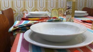 A dining table with a white plate, a bottle of white wine, and a striped tablecloth.