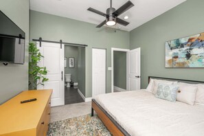 A bedroom with a bed, a TV, a plant, and a ceiling fan. - The Baymiller Row - For 6! (Cincinnati)