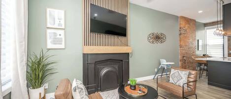 A modern living room with a fireplace, leather sofas, a coffee table, and a dining area with a kitchen in the background.
