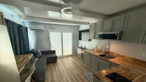 A modern kitchen with a wooden countertop, grey cabinets, and a built-in microwave.