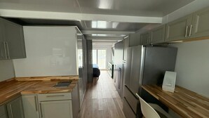 A modern kitchen with grey cabinets, stainless steel appliances, and a wooden countertop.
