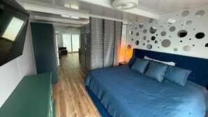 A modern bedroom with a large bed, a TV mounted on the wall, and a unique wall decoration.