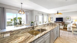 Una cocina moderna con una isla grande, un lavaplatos empotrado y un comedor con un sofá blanco.