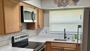 Una cocina moderna con armarios de madera, electrodomésticos de acero inoxidable y una ventana con persianas.