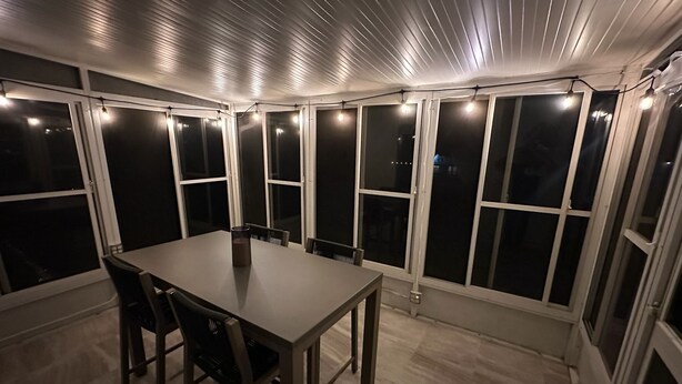 Una habitación con una mesa grande y sillas, varias ventanas y luces colgantes.