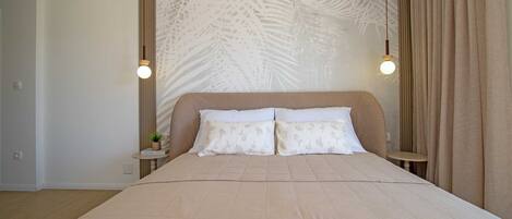A bedroom with a large bed, two bedside tables, a wall with a leaf pattern, and a curtain.