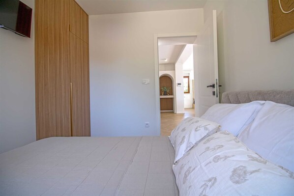 Een slaapkamer met een bed, een houten garderobe en een deur naar een andere kamer.