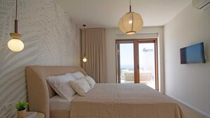 A bedroom with a large bed, a bedside table with a plant, a wall-mounted TV, and a view of the outdoors through a sliding door. - Villa Mood – Pool, Gym & Sauna near Split (Kastel Luksic)