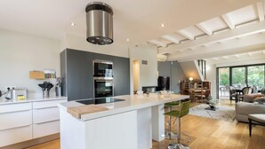 Een moderne keuken met een centraal eiland, inbouwapparatuur en een eethoek met uitzicht.