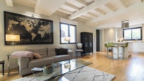 Een ruime woonkamer met een grote wereldkaart, een glazen salontafel en een moderne keuken met barstoelen.