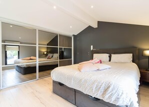 Een moderne slaapkamer met een groot bed, een schuifglazen deur naar een balkon, en een donkere accentmuur.