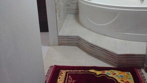 Een badkamer met een bad, betegelde wanden en een kamerbreed tapijt.