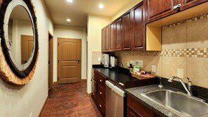 A kitchen with wooden cabinets, a granite countertop, a stainless steel sink, and a built-in dishwasher.
