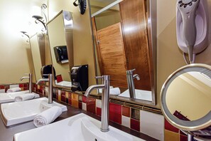 Un baño con dos lavamanos, un espejo y un secador de pelo.