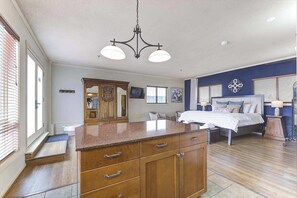 Un dormitorio espacioso con una cama grande, un aparador de madera y una lámpara moderna.