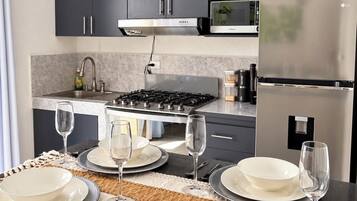 Una cocina moderna con armarios oscuros, una estufa a gas, un microondas y un refrigerador.