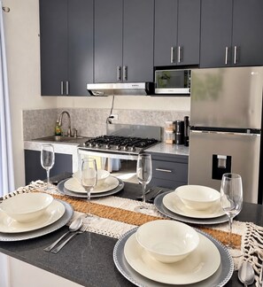 Een moderne keuken met donkere kastjes, een gasfornuis, een magnetron en een koelkast.