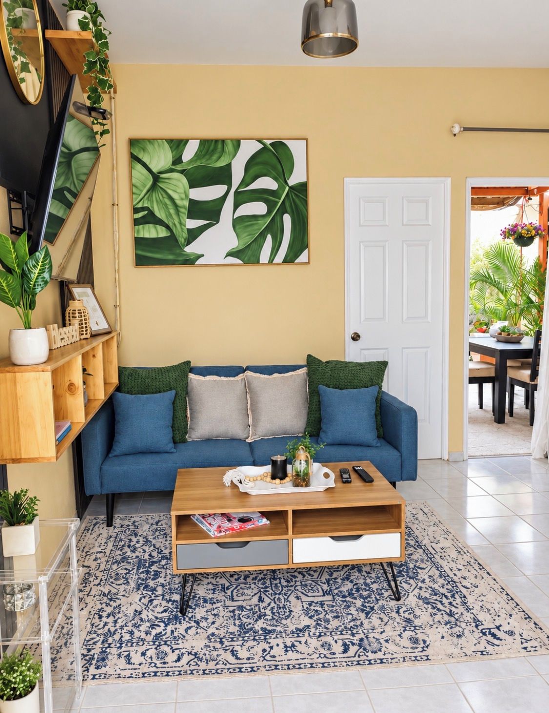 Un soggiorno con un divano blu, un tavolino da caffè e un'ampia parete decorata con piante.