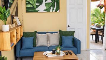 Un soggiorno con un divano blu, un tavolino da caffè e un'ampia parete decorata con piante.