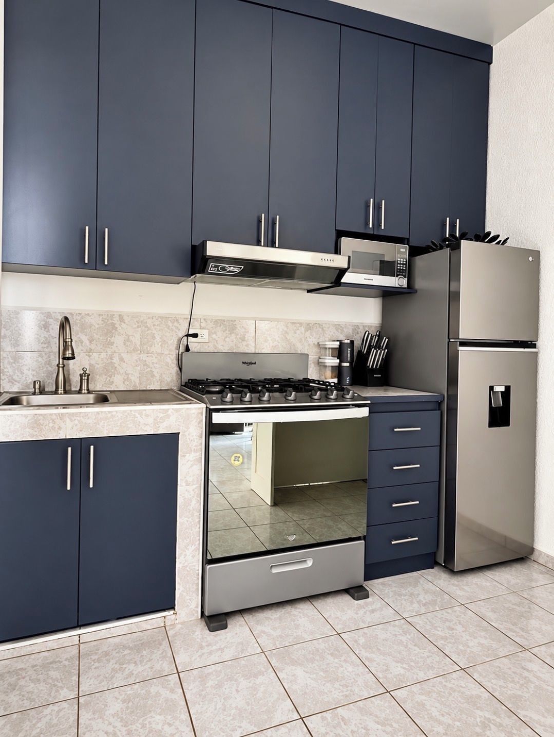 Een moderne keuken met donkere kastjes, een roestvrijstalen fornuis, een magnetron en een koelkast.