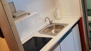 Una cocina compacta con un lavamanos, una estufa y una pequeña encimera.