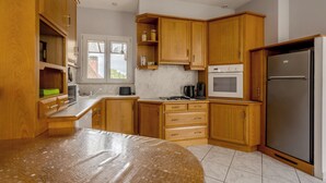 A kitchen with wooden cabinets, a stainless steel refrigerator, and a tiled floor.