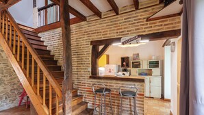 Una cocina con pared de ladrillo, escalera de madera y dos taburetes de bar.