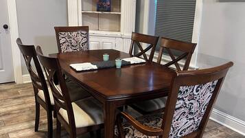 Une salle à manger avec une table et des chaises en bois, une bibliothèque et un lustre.