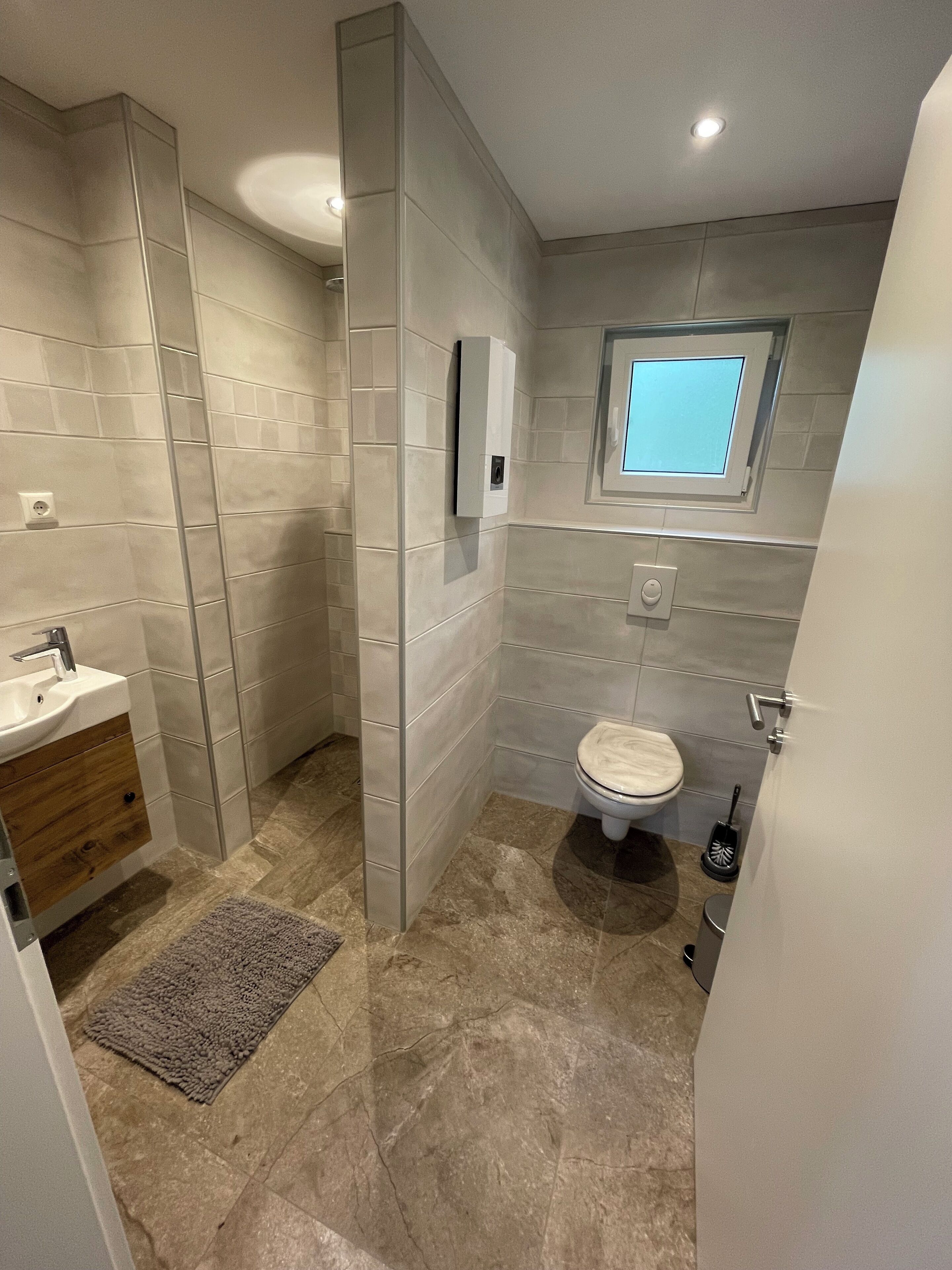 Een moderne badkamer met toilet, wastafel en douche.