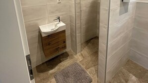 A modern bathroom with a sink, wooden vanity, and a shower area.