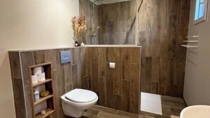 Un baño moderno con diseño de pared de madera, un inodoro, ducha y bañera.